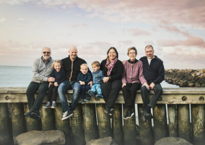 Billede af familie, siddende på bølgebryder i aftensolen på Marina stranden i Bogense