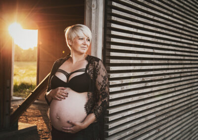 Billede af gravid dame der staar op af en trea veag ved solnedgang