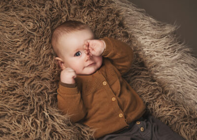 Billede af lille dreng der ligger paa et pels teappe
